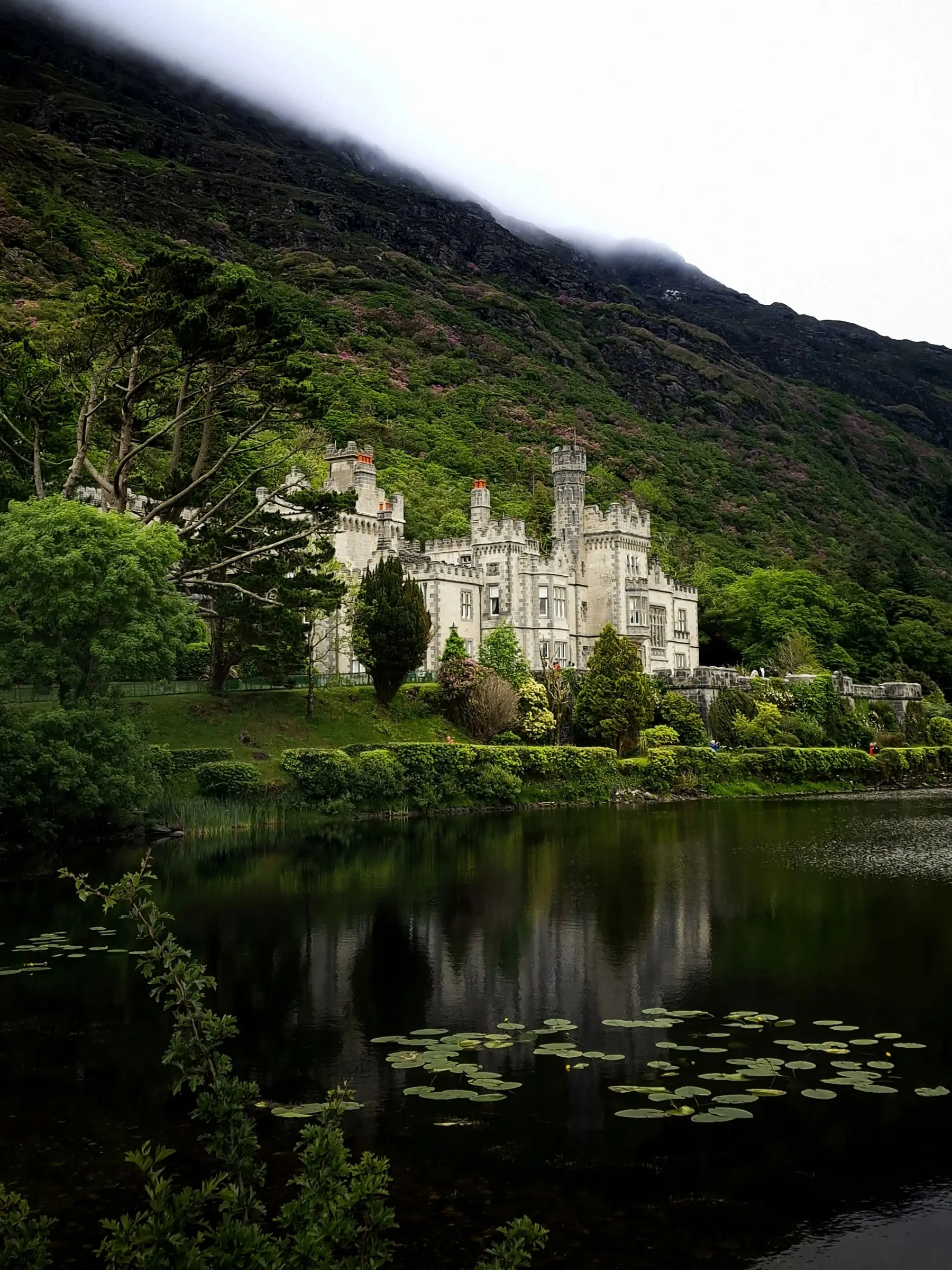 Kylemore Abbey beneath a misty mountain, reflected in the lake, in Connemara